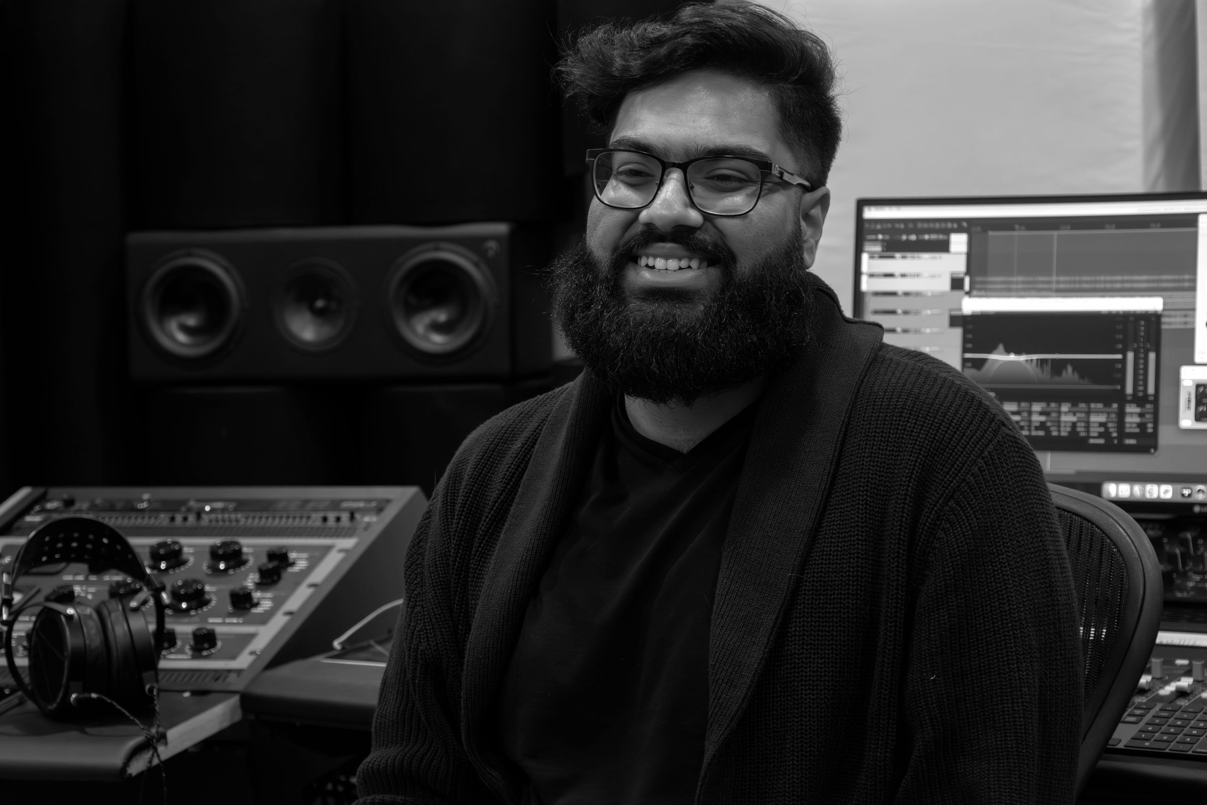 Sam Kumar Tandon smiling at the mastering desk in his studio